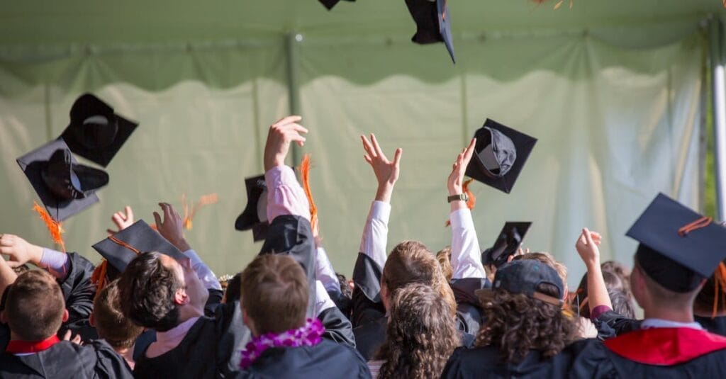 Group of graduates celebrating by tossing caps into the air during a graduation ceremony.