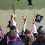 Group of graduates celebrating by tossing caps into the air during a graduation ceremony.