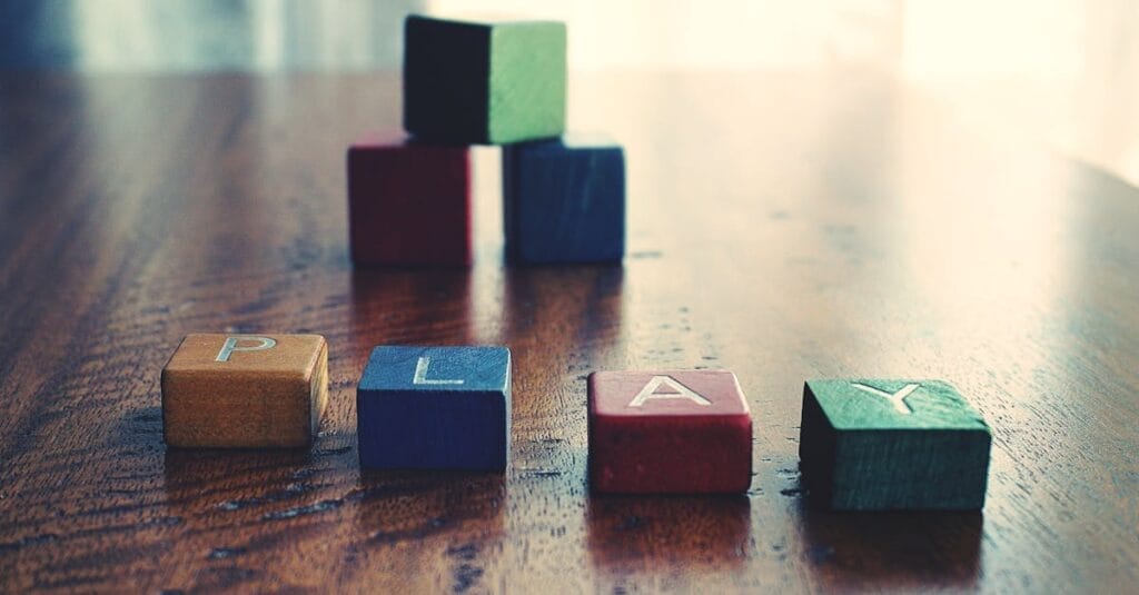 A vibrant still life of wooden alphabet blocks spelling 'PLAY' on a wooden surface.