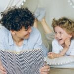 A joyful mother and son enjoying reading together in a cozy indoor tent setting.