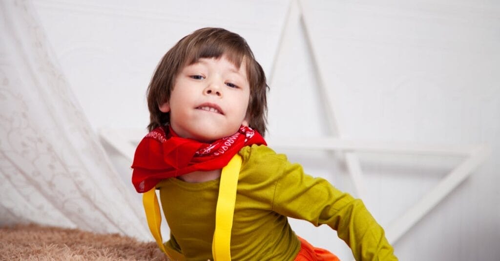 Young child posing indoors with a playful expression and bright clothing.