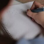 A student writes mathematical notes in a notebook using a pen, focus on studying.