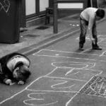 Two children play hopscotch with chalk on a street in La Rochelle, France.