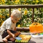 A young boy playing with a colorful puzzle outdoors on a sunny summer day.