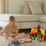 A child enjoys playtime with toy trucks and blocks in a cozy living room setting.