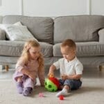 Two kids engaging with a toy in a cozy living room setting, fostering creativity.