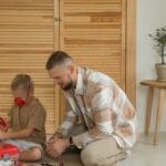 Father and son enjoying quality time assembling a toy kit indoors. Perfect for family and lifestyle themes.