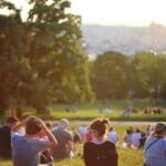 People relaxing and enjoying a sunny day in a bustling city park.