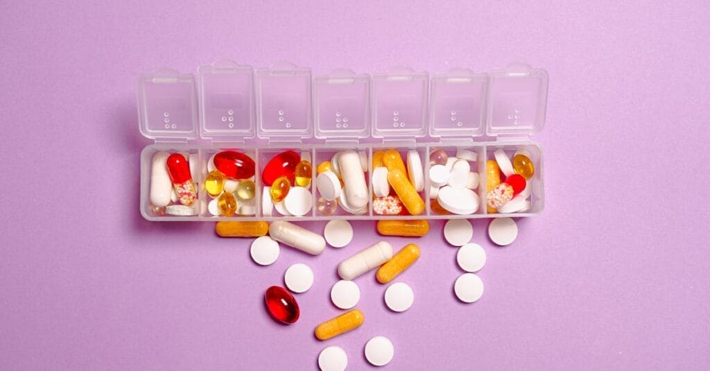 A daily pill organizer filled with various pills and capsules on a purple background. Ideal for healthcare topics.