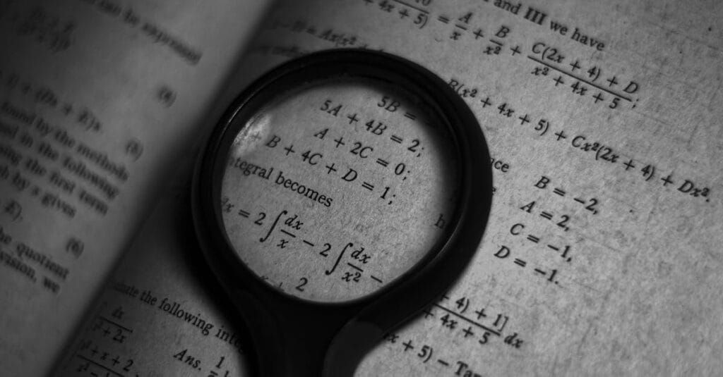 A magnifying glass focuses on mathematics formulas in a book, enhancing study and exploration.