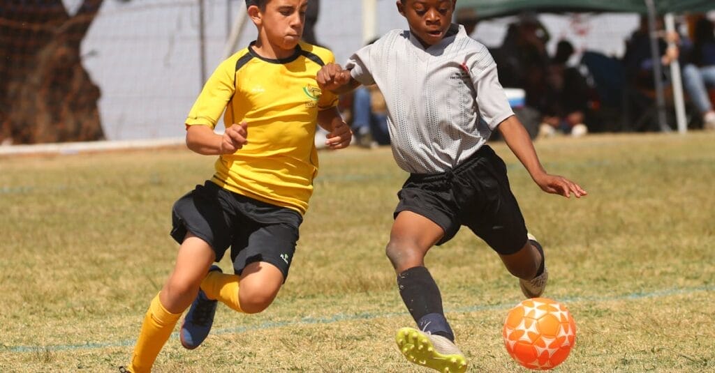 Two young boys energetically competing in a soccer match on a grassy field.