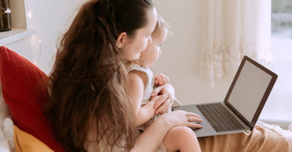 Mother and daughter enjoy quality time together using a laptop indoors.