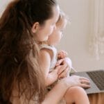 Mother and daughter enjoy quality time together using a laptop indoors.