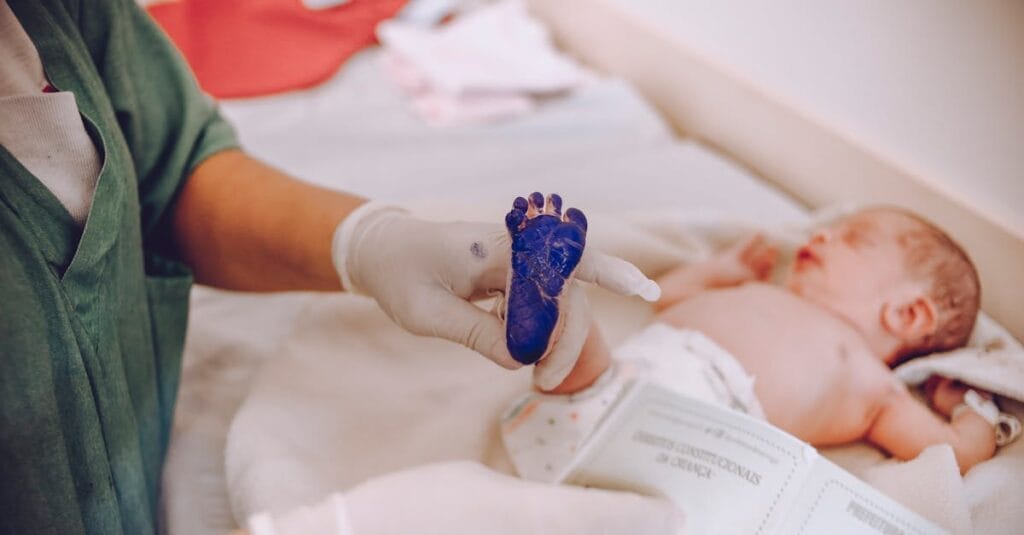 Medical professional taking footprint of a newborn baby in hospital setting.