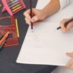 A mother and child drawing together at a table, emphasizing early education and creativity.