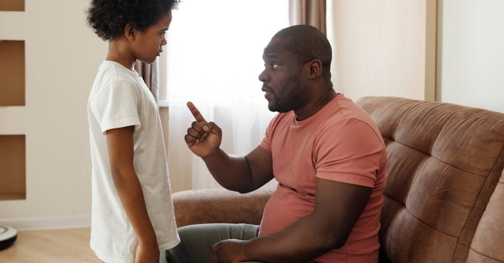 Father and son engaged in a heartfelt conversation on the sofa, illustrating parenting in a loving family setting.