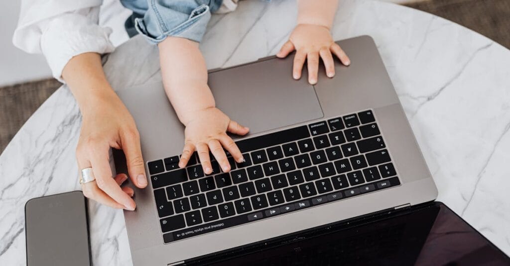 Top view of a parent and a child's hands on a laptop keyboard, symbolizing digital learning.