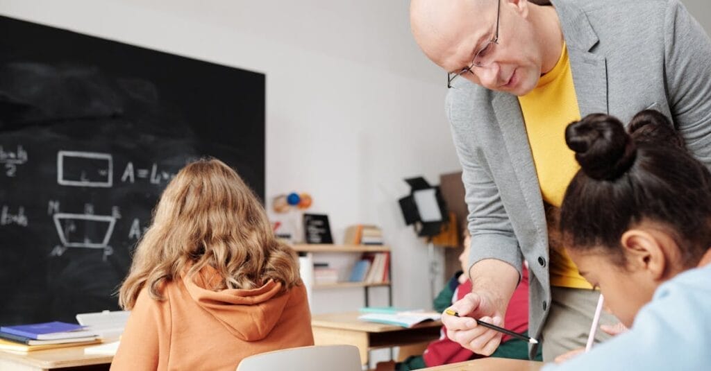 Teacher helping students in classroom, enhancing learning with personalized attention.