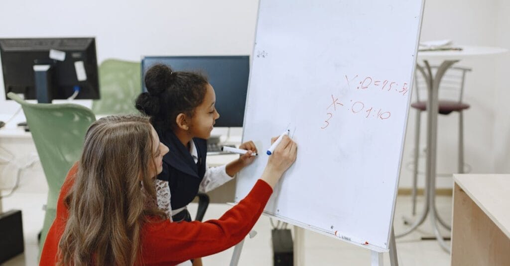 A teacher helps a student with math on a whiteboard in a classroom setting.