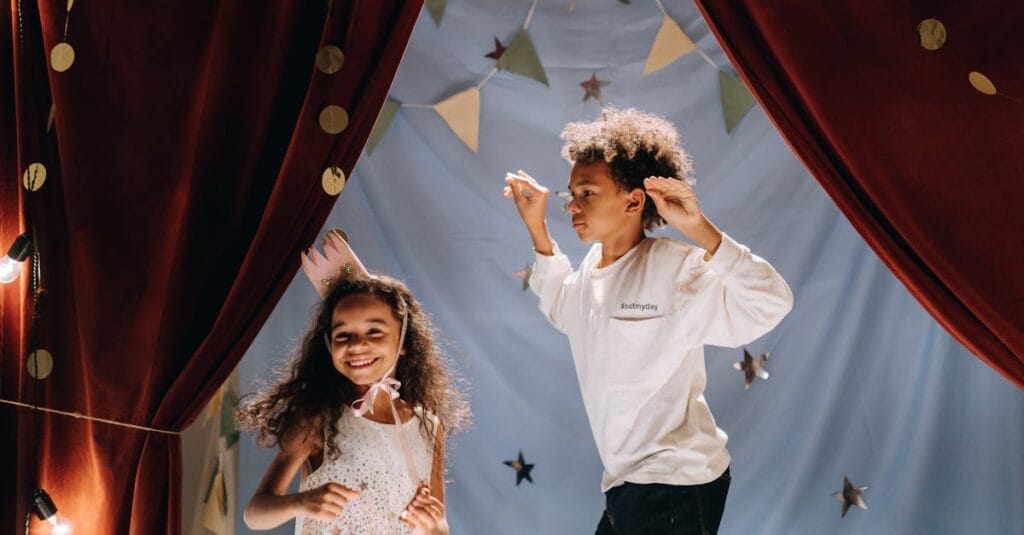 Two joyful kids performing in a homemade theater setup with costumes and curtains, having a fun time indoors.