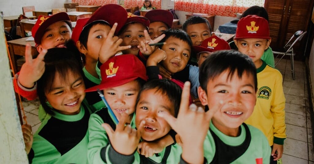 Group of Indonesian children smiling and posing for the camera in a classroom setting.