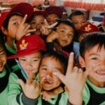 Group of Indonesian children smiling and posing for the camera in a classroom setting.