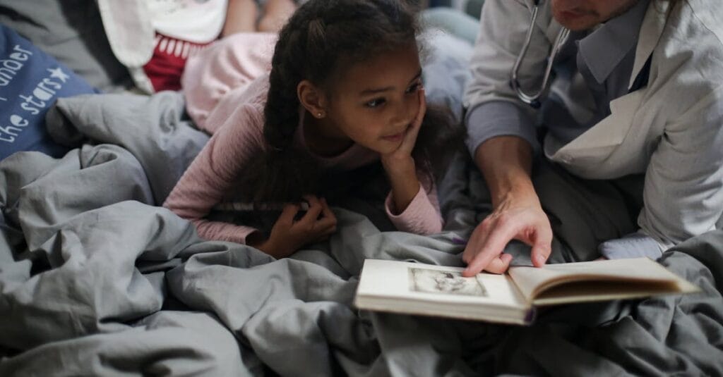 A father and daughter enjoy quality time reading a book together in a cozy setting.