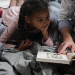 A father and daughter enjoy quality time reading a book together in a cozy setting.