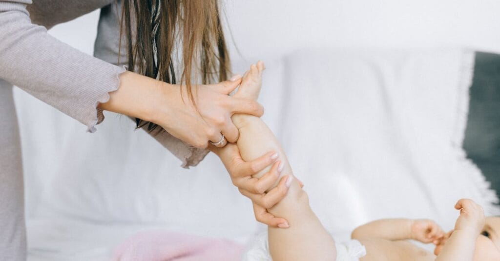 A mother gently massages her baby's foot, promoting relaxation and bonding in a cozy setting.