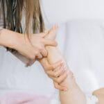 A mother gently massages her baby's foot, promoting relaxation and bonding in a cozy setting.