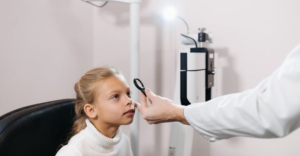 Caucasian girl undergoing an eye exam by a professional in a clinical setting.