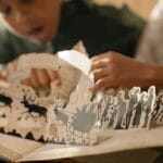 Two children engaged with a pop-up book, capturing the magic of reading indoors.