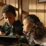 Two children enjoying a reading session together in a warm and cozy room.