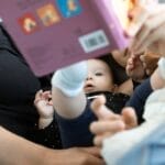 A baby and family reading together, promoting love and education. Cozy indoors setting.