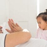 A tender moment shared between a father and his daughter in a sunlit bedroom.