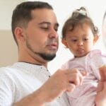 Father lovingly feeding his baby daughter in a modern kitchen.