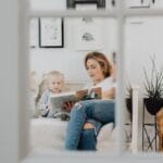 A mother and her daughter reading together in a cozy bedroom setting, fostering learning and bonding.