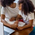 A mother and daughter bonding over homework at the dining table.