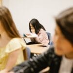 A student sits alone in a school classroom, depicting solitude and contemplation.