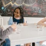 Three children engage in lively conversation during snack time at school.