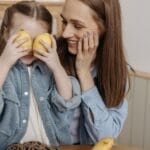 A mother and daughter share a joyful moment at home with playful lemons.