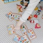 A child engaging with educational flashcards and colorful stickers on a bed.