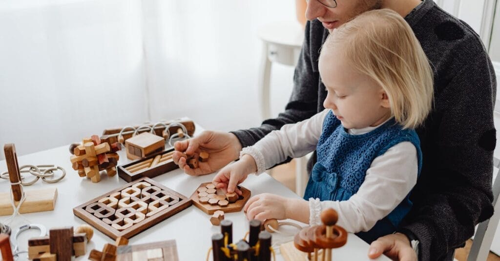 A father and child enjoying wooden puzzles together at a table indoors, fostering creativity and learning.