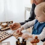 A father and child enjoying wooden puzzles together at a table indoors, fostering creativity and learning.