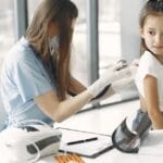 Young girl in clinic receiving a checkup from a female doctor with stethoscope.