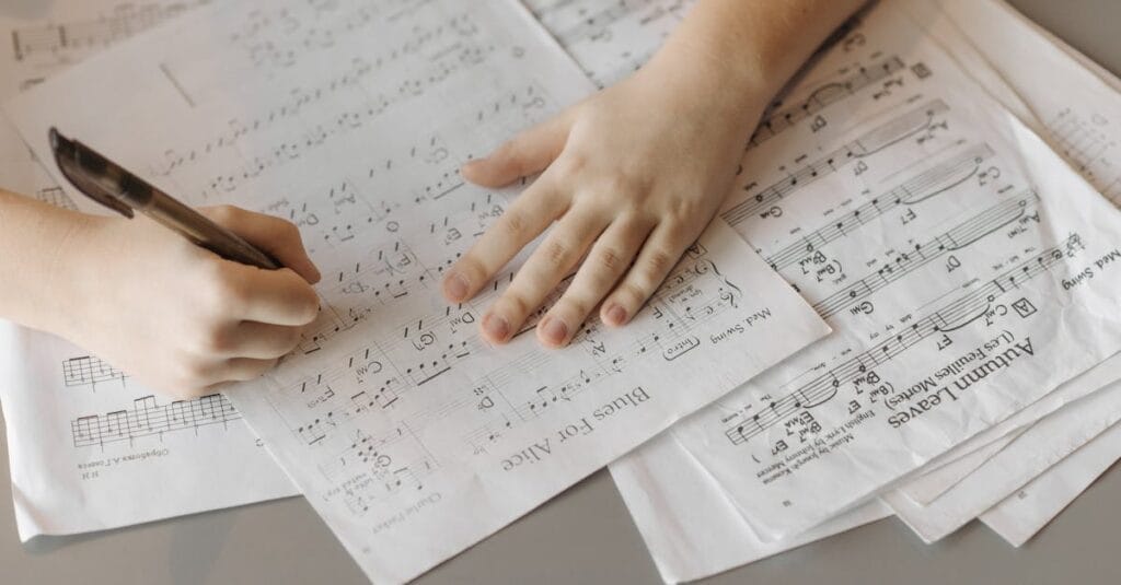 A child writes on sheet music, enhancing creativity through music composition.