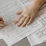 A child writes on sheet music, enhancing creativity through music composition.