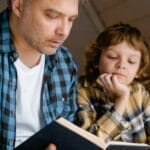 A father and son sharing a tender moment reading a bedtime story together.