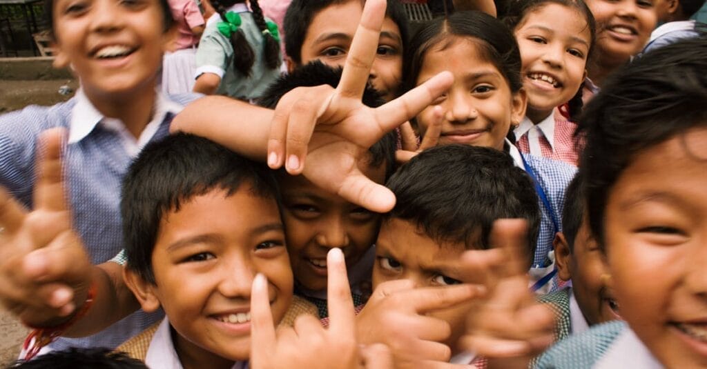 A joyful group of children smiling and making playful gestures outdoors in Namarjung, Nepal.