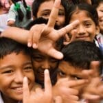 A joyful group of children smiling and making playful gestures outdoors in Namarjung, Nepal.